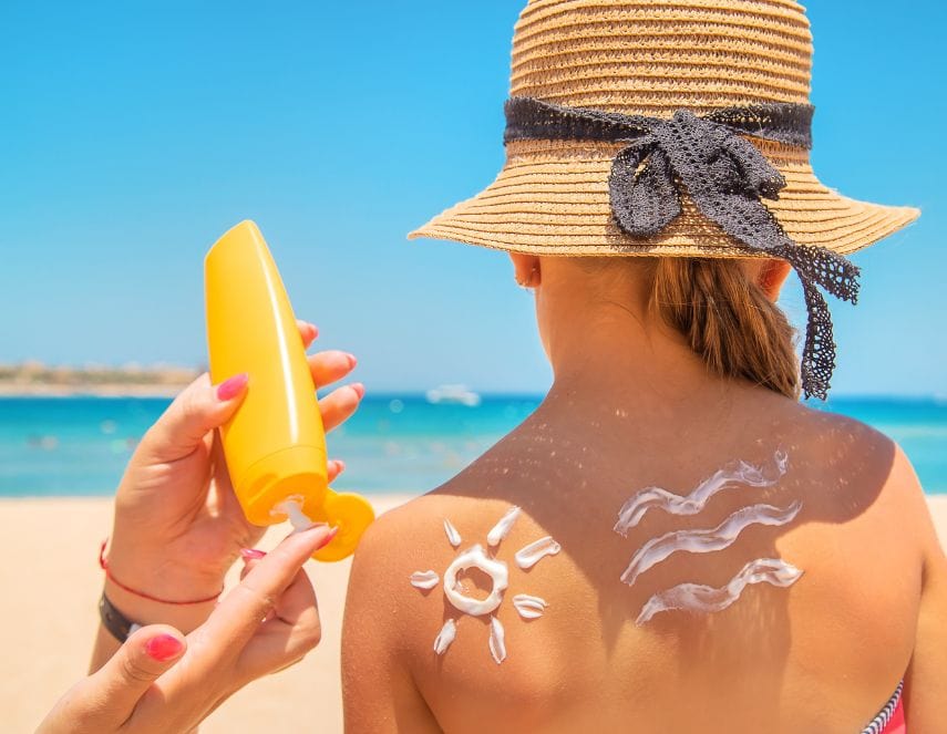 Photo à la plage d'un parent qui met de la crème solaire à son enfant